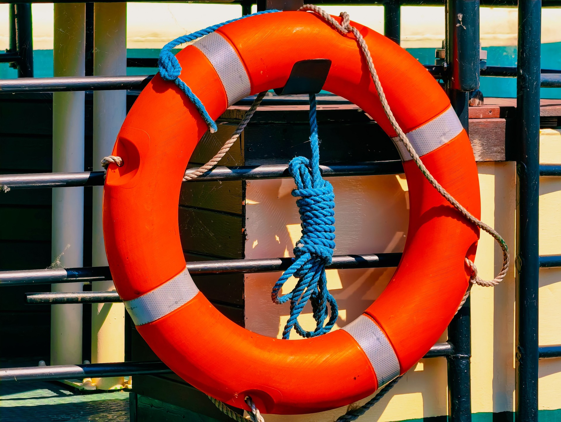 Bright Orange Lifebuoy Ring on Ship Railings – Marine Safety Equipment for Nautical and Coastal Themes.